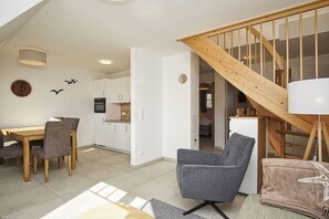 A modern interior with a dining area, kitchen, and a staircase. - Beachfront vacation rental with a balcony, access to the pool and sauna - Rex Rugia H-1010 - (Göhren)