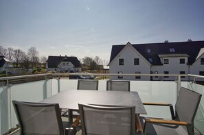 A rooftop terrace with a table and chairs, overlooking a residential area with houses and parked cars. - Beachfront vacation rental with a balcony, access to the pool and sauna - Rex Rugia - Rex Rugia (Göhren)
