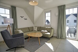 A modern living room with a sectional sofa, a round coffee table, and a floor lamp. - Beachfront vacation rental with a balcony, access to the pool and sauna - Rex Rugia - Rex Rugia (Göhren)