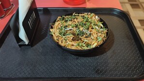 Una ciotola di noodles su un vassoio nero con superficie strutturata.