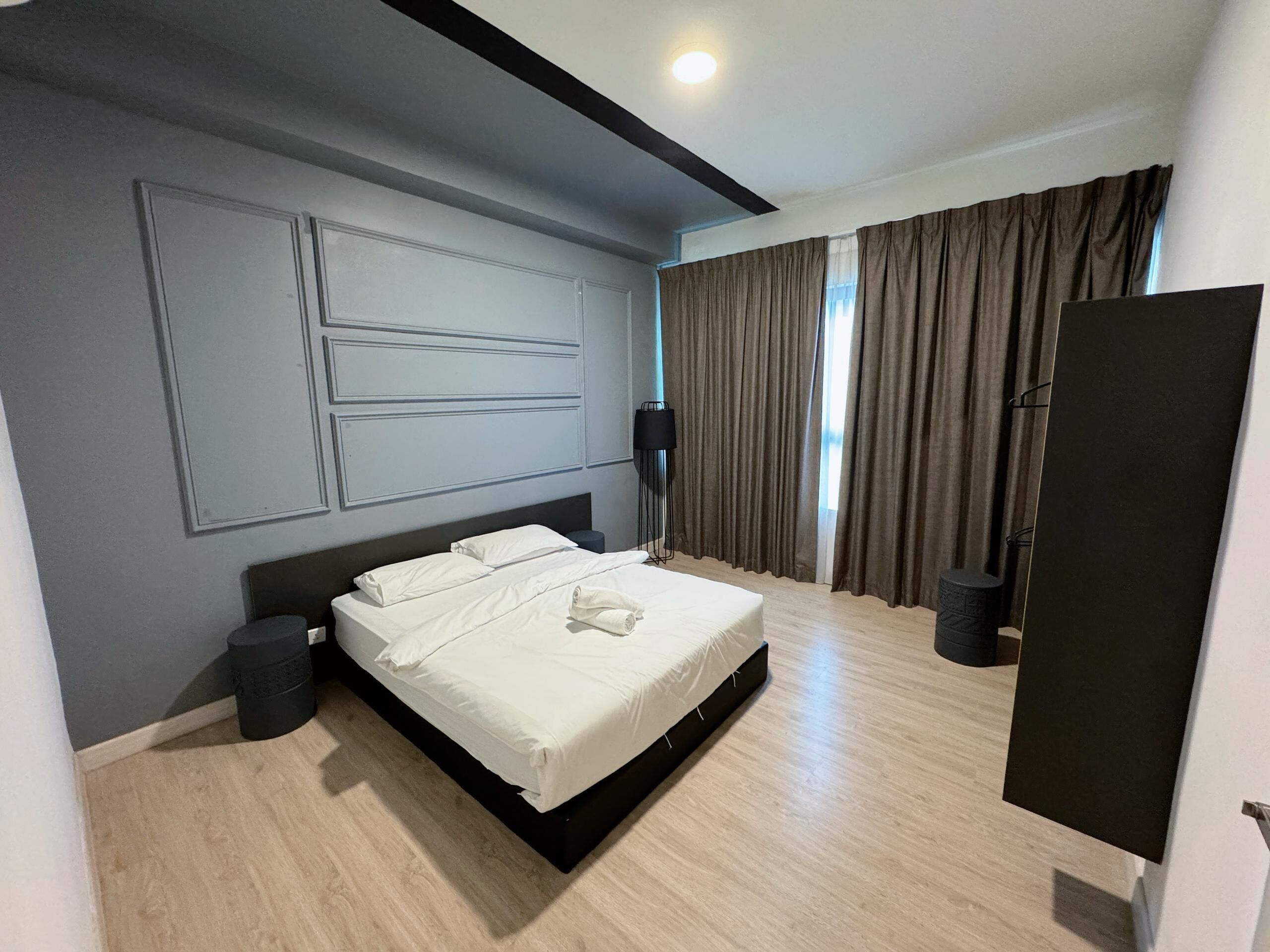 A modern bedroom with a large bed, a dark headboard, and a large window with curtains.