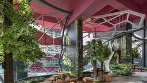 An indoor space with wooden tables and benches, surrounded by greenery and a modern architectural design with geometric patterns. - Comfy Arte Plus Ampang City 7PAX-3BR-2CP (Kuala Lumpur)