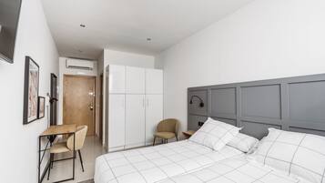 A modern bedroom with a large bed, a desk, and a chair.