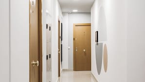 Un couloir aux murs blancs, aux portes en bois et au sol carrelé.