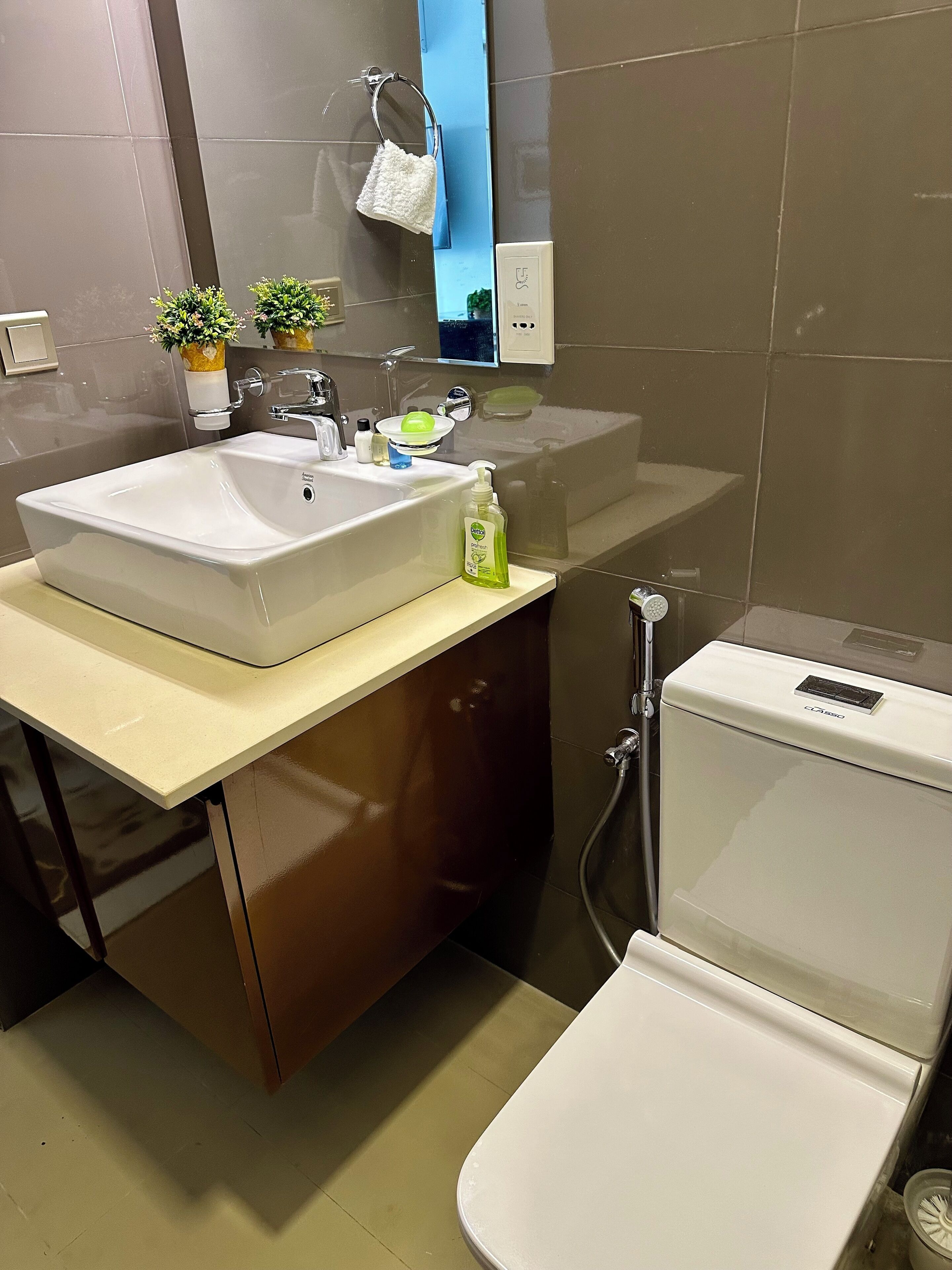 A modern bathroom with a double sink, a toilet, and a mirror above the sink.