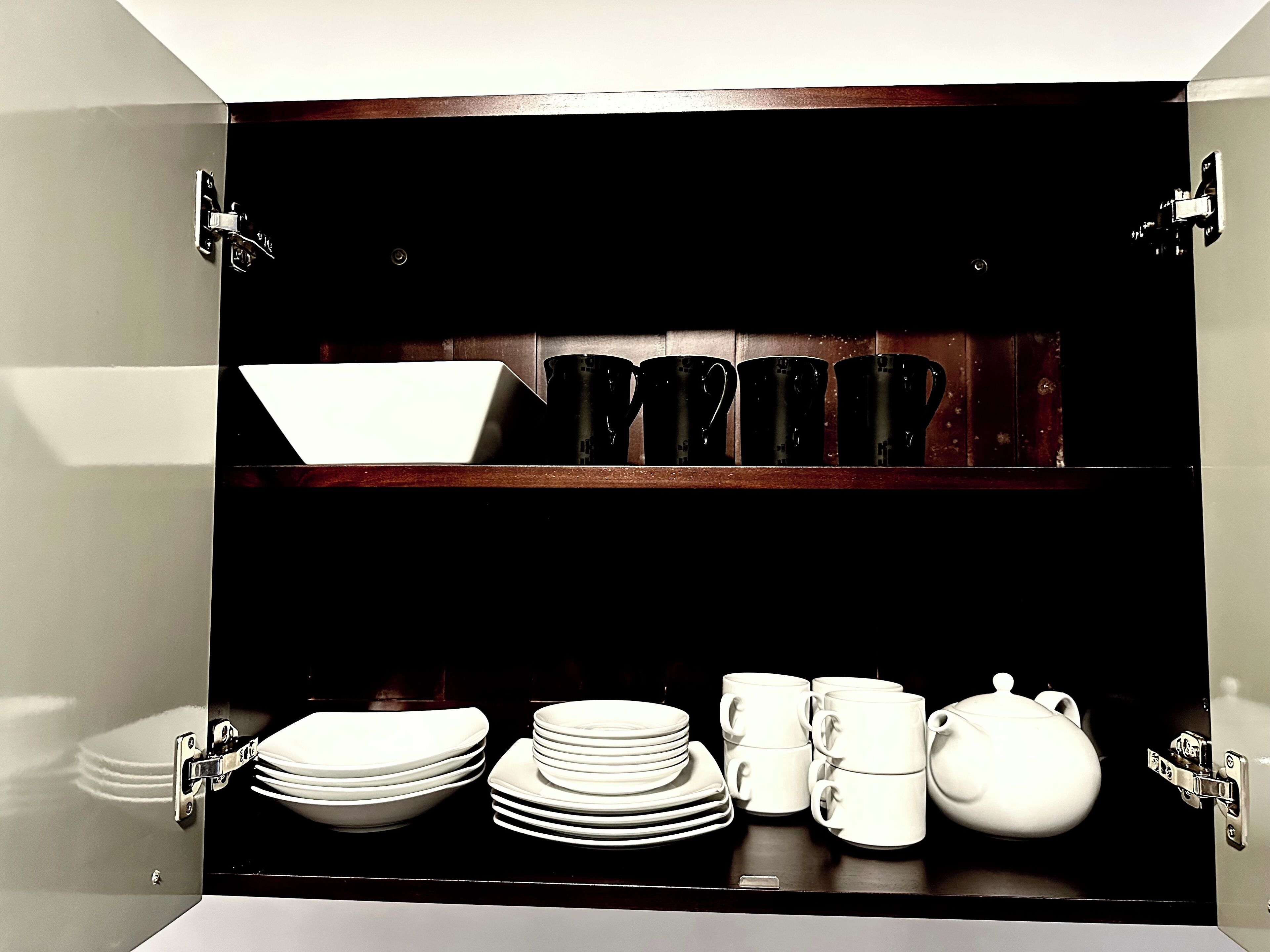 A kitchen cabinet with shelves holding plates, bowls, and cups.