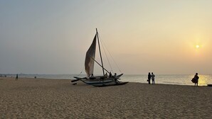 Una playa con un velero anclado cerca de la orilla.