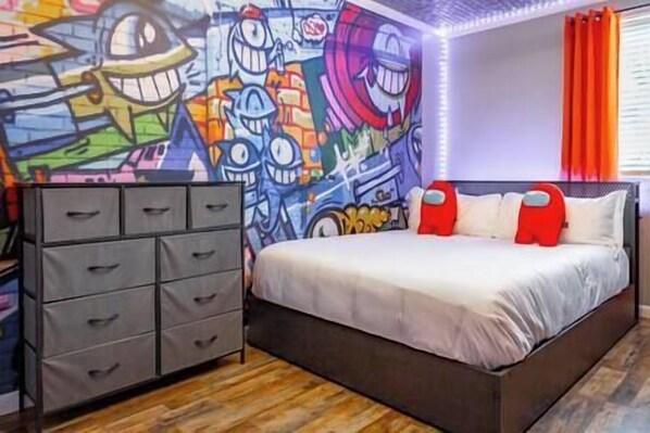 Un dormitorio con cama, cómoda y un mural colorido en la pared.