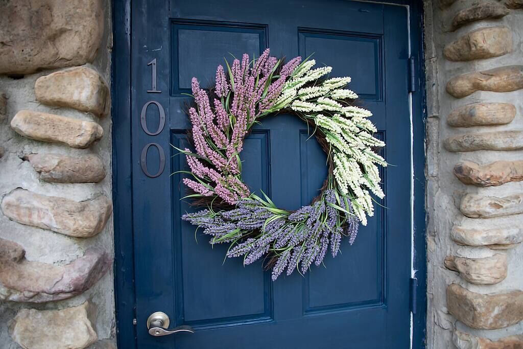 A door with a wreath made of purple and white flowers.