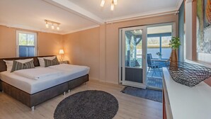 Ein Schlafzimmer mit Bett, Nachttischlampe und Blick ins Freie.