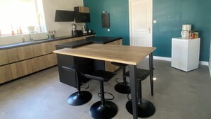 Una cocina moderna con una mesa de madera y taburetes negros, un refrigerador blanco y una pared de acento color turquesa.