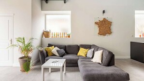 Una sala de estar moderna con un sofá seccional gris, una mesa de centro blanca y una planta en maceta.