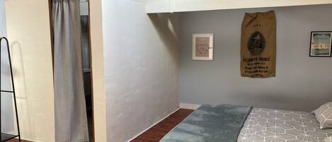 A bedroom with a lofted sleeping area, a bed with a geometric patterned bedspread, a blue throw blanket, and a wooden ladder.