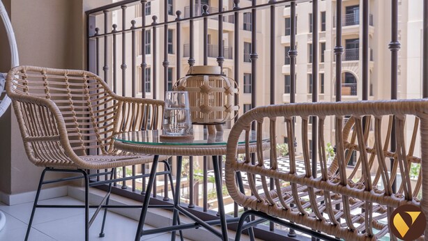 A balcony with wicker chairs and a table, a glass of water, and a decorative lamp. - Vogue | Jadeel Madinat Jumeirah near Burj Al Arab (Dubai)