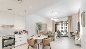 Eine moderne Wohnung mit Küche, Essbereich und Wohnzimmer. Sie verfügt über einen Herd, Stühle, ein Sofa und ein großes Fenster.