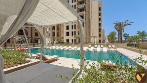 A pool area with lounge chairs, a lifebuoy, and a covered seating area. - Vogue | Jadeel Madinat Jumeirah near Burj Al Arab (Dubai)