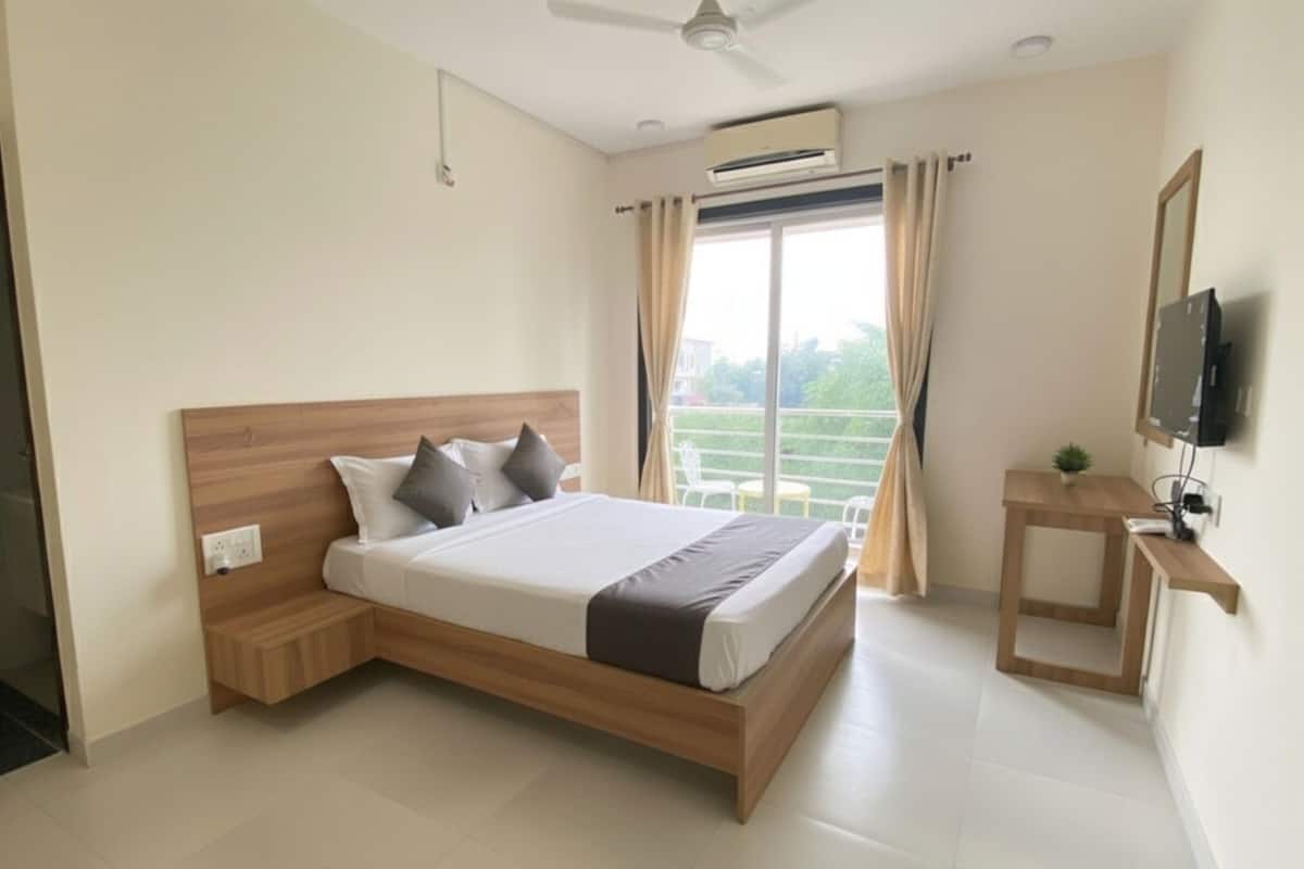 A modern hotel room with a wooden bed, a small bedside table, a TV, and a balcony with curtains.