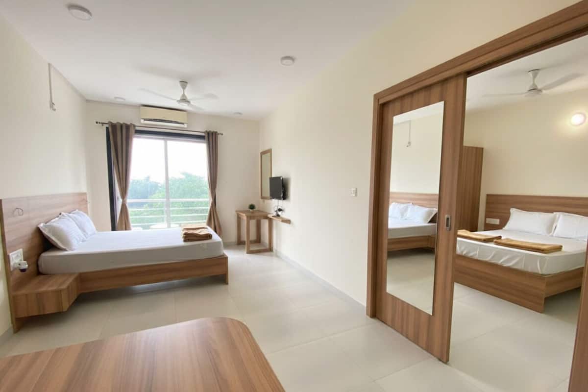 A modern hotel room with a large bed, a desk, and a view of the outdoors.