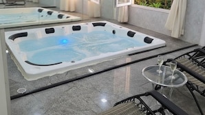 Área de spa com duas banheiras de hidromassagem e uma mesa de vidro com dois copos.