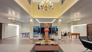 Um hall amplo com uma estrutura decorativa central, mesas e cadeiras.