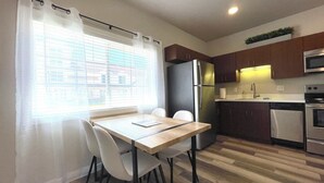 Een kleine keuken met een eettafel, stoelen, een koelkast, een oven en een magnetron.