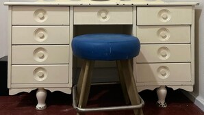 A beige vanity with a round mirror, a blue stool, and multiple drawers. - Arada Ayvalık (Ayvalik)