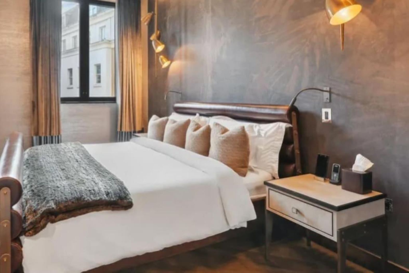A bedroom with a bed, bedside table, lamp, and a window with curtains.