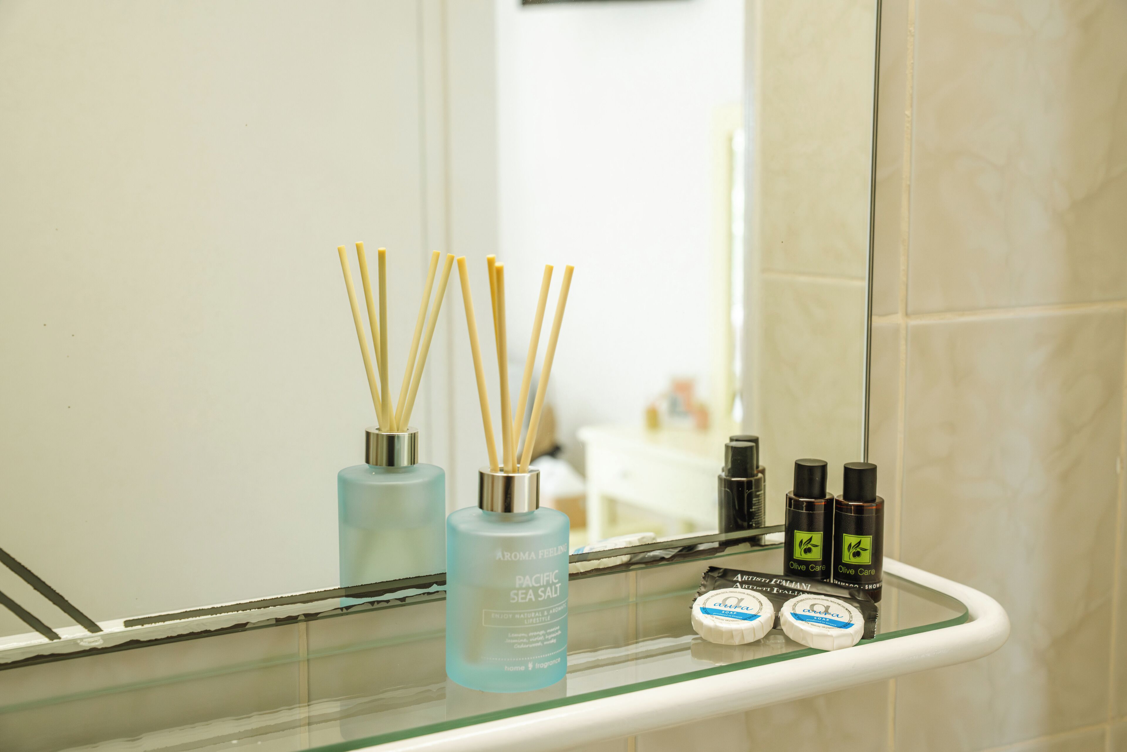 A bathroom shelf with a Pacific Sea Salt bottle, two olive oil bottles, and a soap bar.