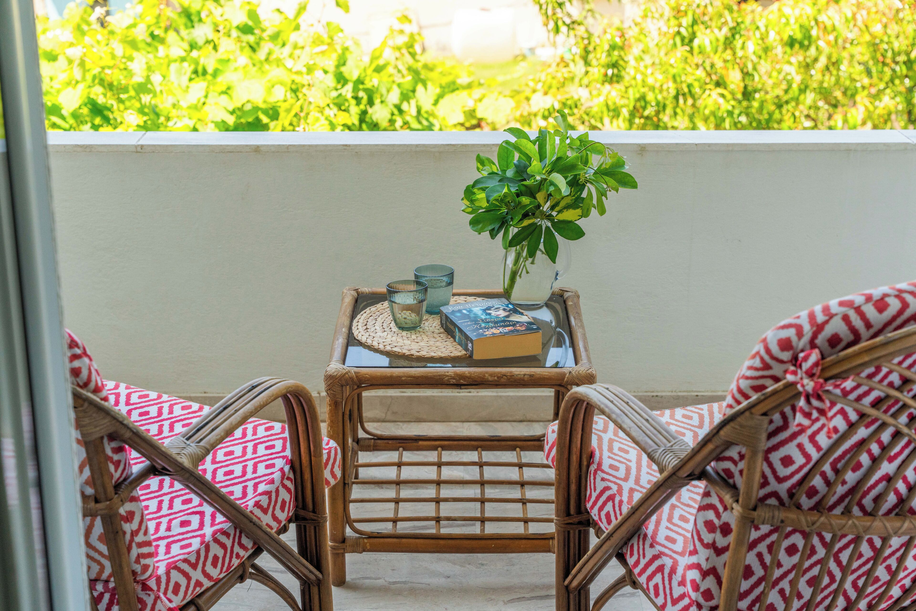 A balcony with wicker furniture, a small table with a plant, and a book.