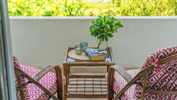 A balcony with wicker furniture, a small table with a plant, and a book.