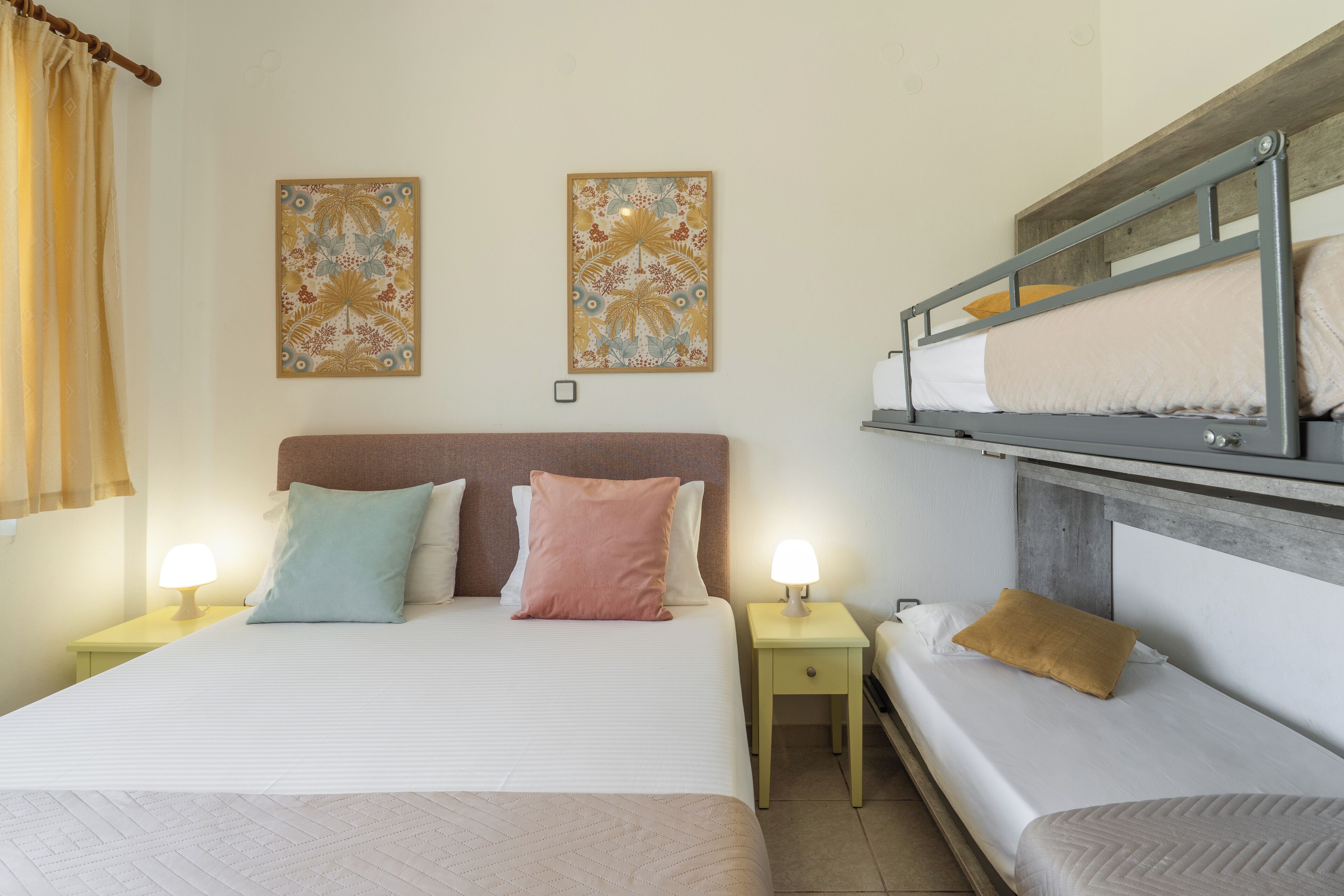 Une chambre avec un lit superposé, deux tables de chevet avec des lampes et deux œuvres d’art accrochées au mur.
