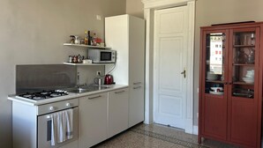 A kitchen with a stove, microwave, and cabinets. There is a door with a glass panel on the right. - La Giulietta- Penthouse (Salerno)