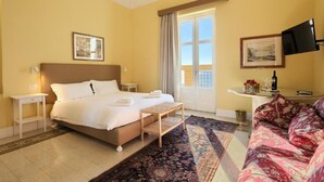 A hotel room with a bed, a small table, a sofa, a TV, and a window with curtains. - La Giulietta- Penthouse (Salerno)