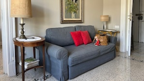 A grey sofa with red cushions, a lamp, a framed painting, and a small table with a magazine. - La Giulietta- Penthouse (Salerno)
