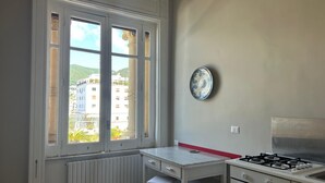 A small kitchen with a window, a radiator, a stove, and a white countertop. - La Giulietta- Penthouse (Salerno)