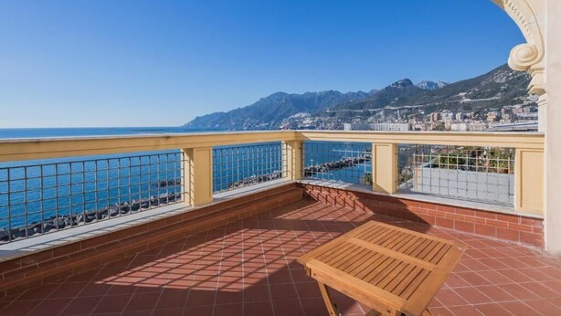 A balcony with a wooden table, a tiled floor, and a view of the sea and mountains. - La Giulietta- Penthouse (Salerno)