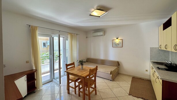 A compact living space with a dining area, kitchenette, and a sliding glass door leading to a balcony. - Apartment Velvet Vista 1 (Novi Vinodolski)