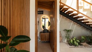Ein modernes Interieur mit einer Holztreppe, einer kleinen Spüle und einer Pflanzenanordnung.