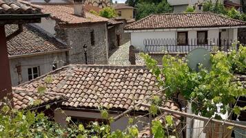 A courtyard with a stone building featuring a bell tower, surrounded by residential houses with tiled roofs.