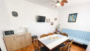 A compact kitchen with a microwave, coffee maker, and a dining table with chairs. - Apartmani Talia Crikvenica (Crikvenica)