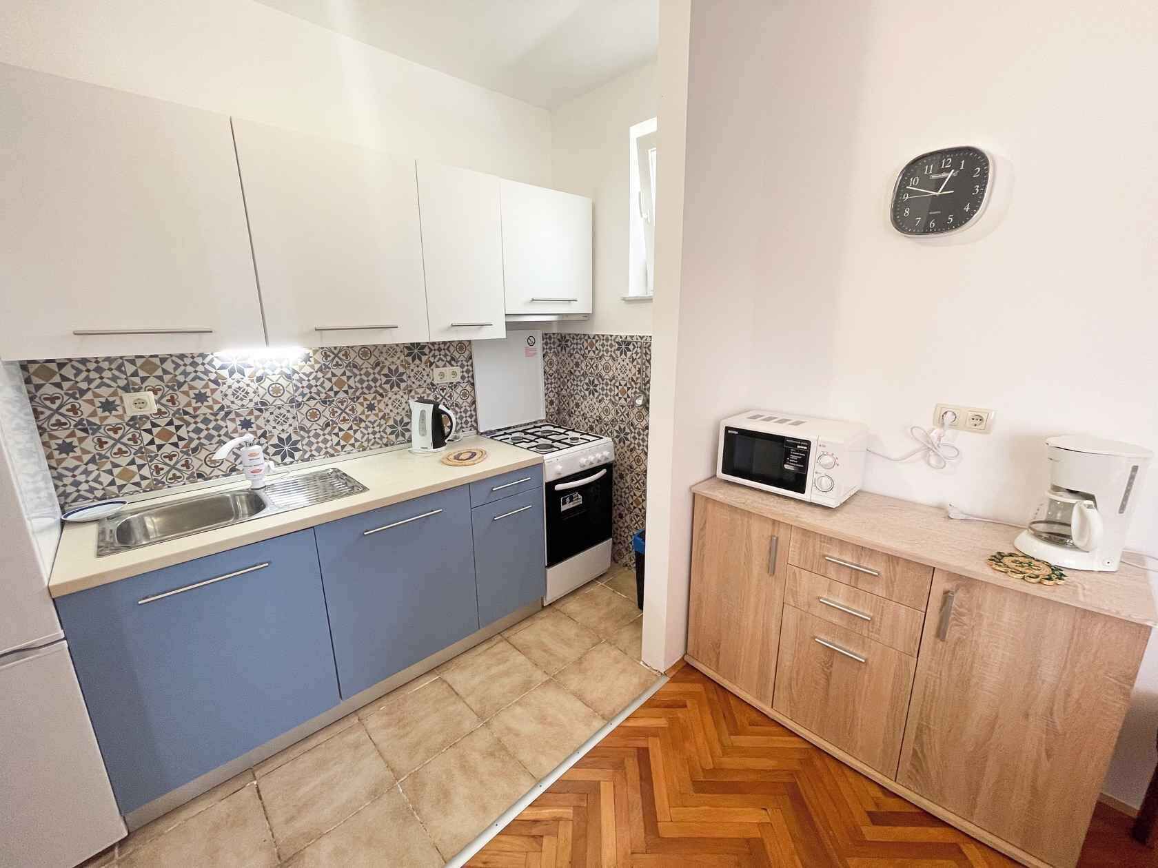A compact kitchen with a sink, stove, microwave, and cabinets.