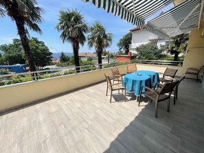Ein Balkon mit Tisch und Stühlen, der auf ein Wohngebiet mit Palmen und Häusern blickt.