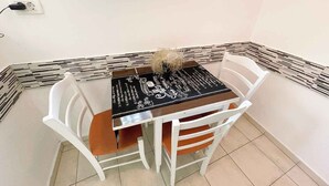 A small dining area with a table and two chairs, a window above the table, and a patterned border along the wall. - Apartmani Talia Crikvenica (Crikvenica)