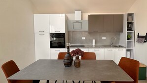 Eine moderne Küche mit weißen Schränken, einem eingebauten Backofen und einer grauen Arbeitsplatte.