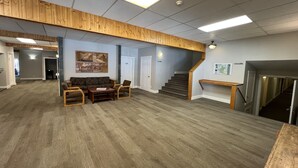 Ein geräumiges Zimmer mit Holzboden, einer Treppe und einer Sitzecke mit Sofa und Sesseln.