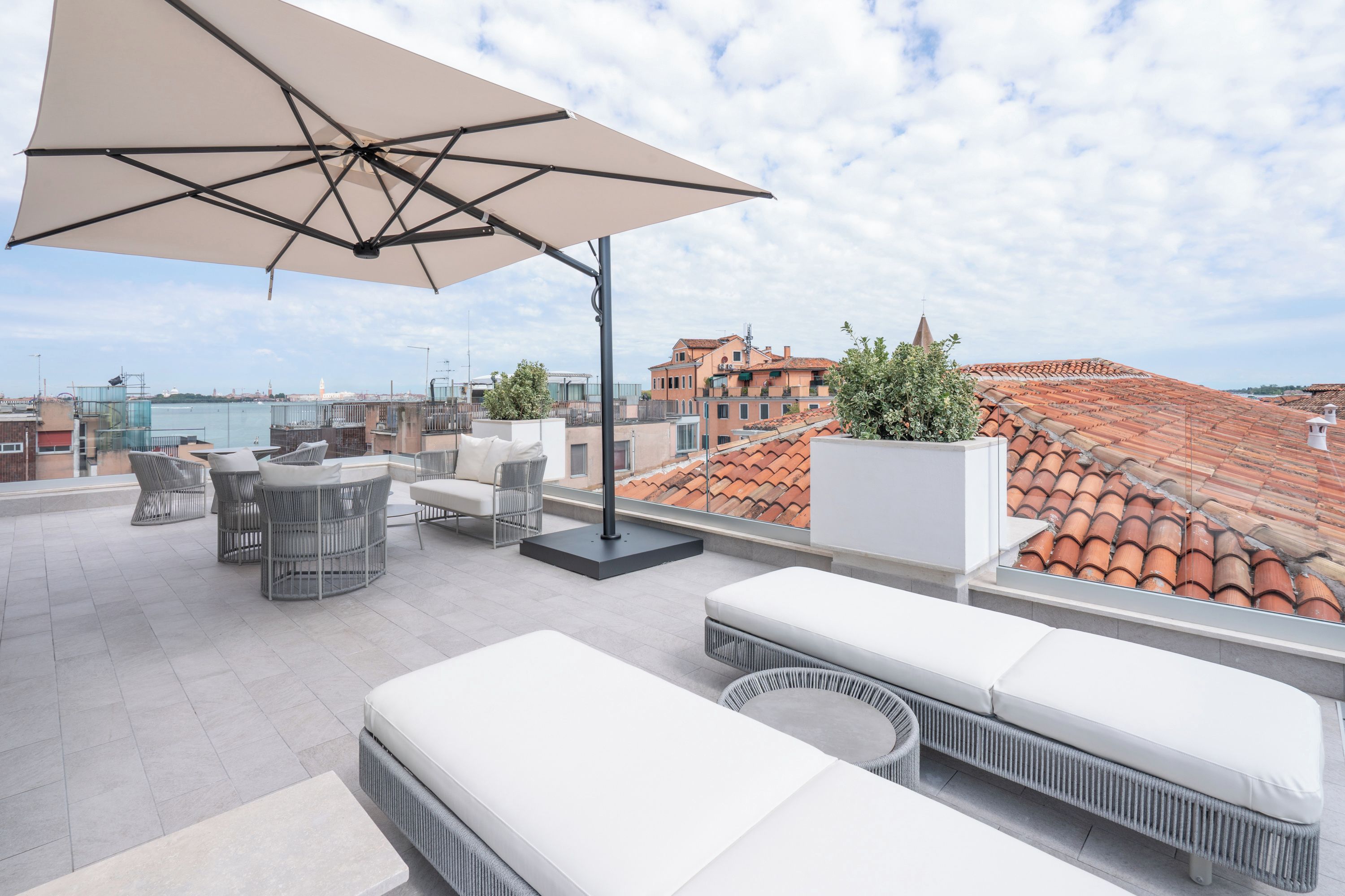 A rooftop terrace with outdoor furniture, a large umbrella, and a view of the cityscape.