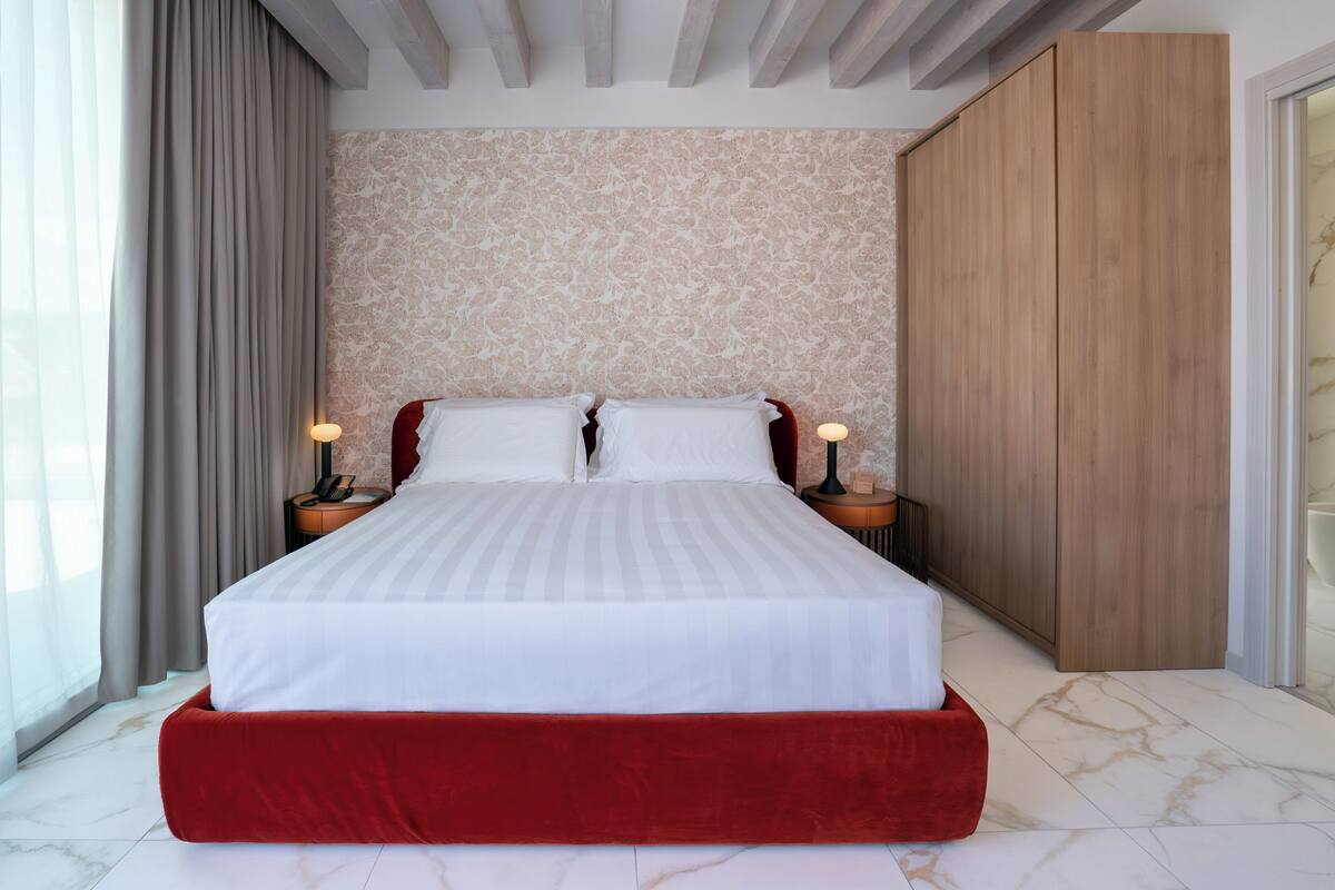 Une chambre d’hôtel moderne avec un grand lit, une armoire en bois et un sol en marbre.