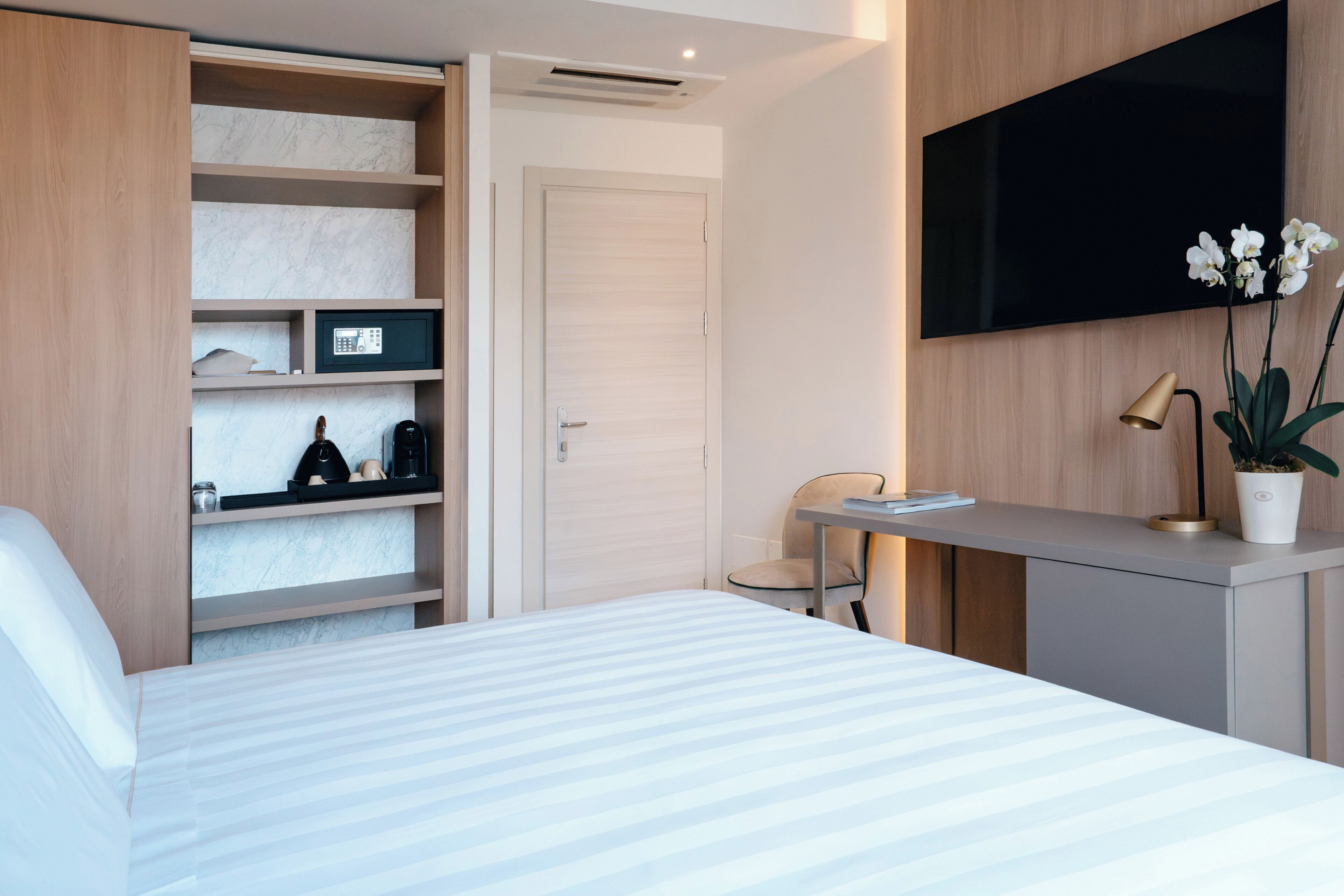 Una habitación de hotel moderna con cama, escritorio, silla, televisor y planta.