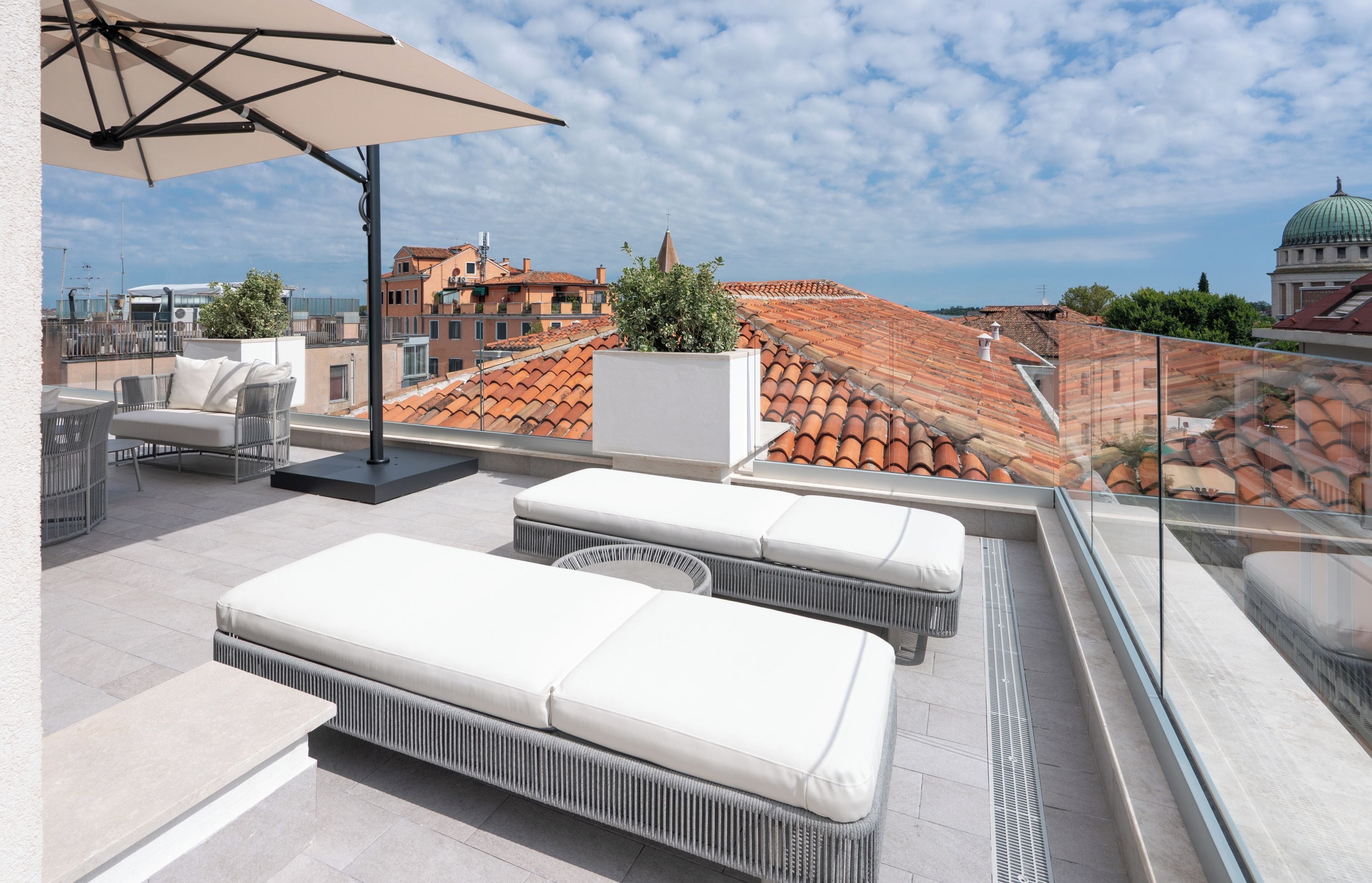 A rooftop terrace with outdoor seating, a large umbrella, and a view of the cityscape.