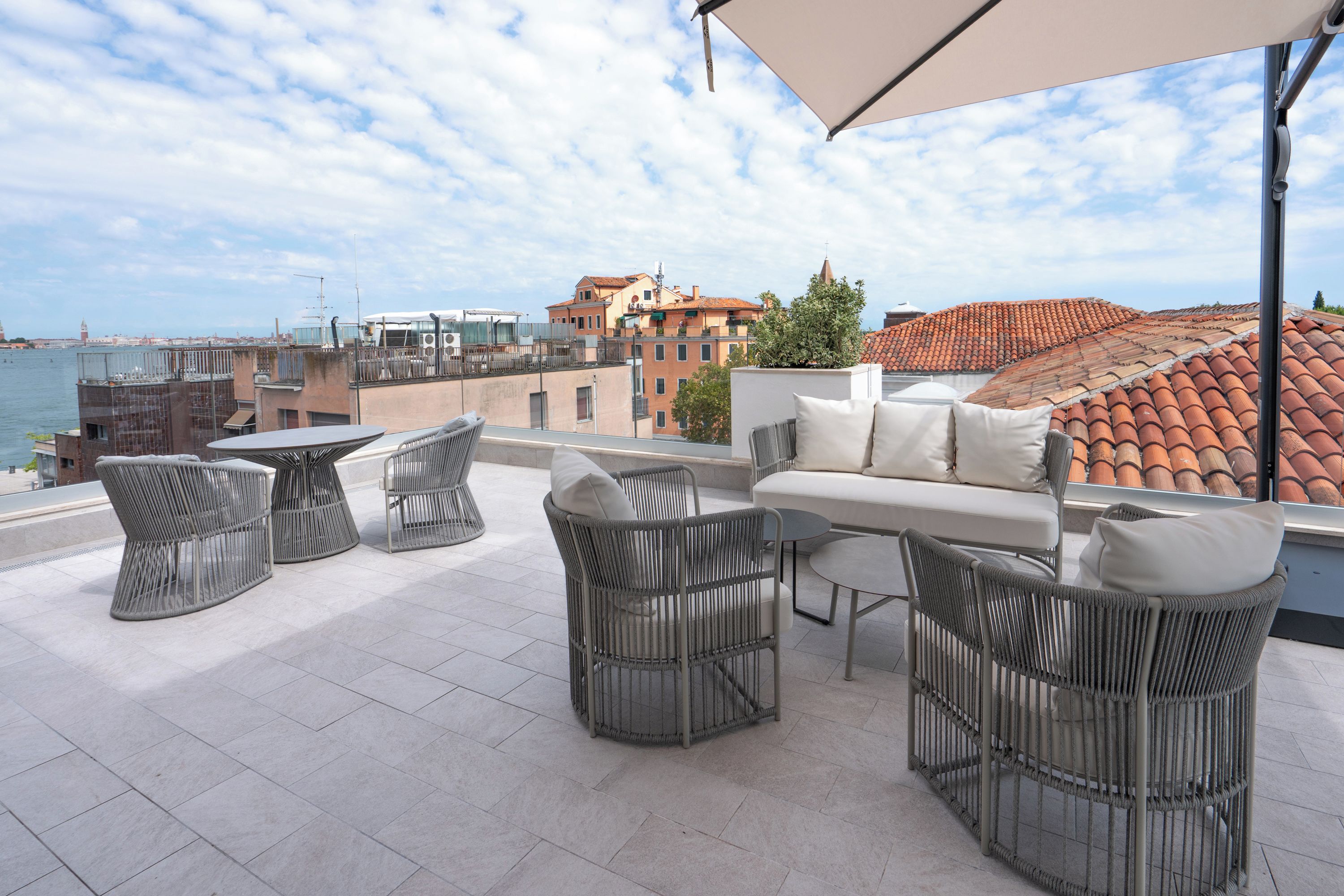 A rooftop terrace with outdoor furniture, a view of the city, and a body of water.